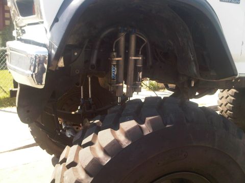 1986 Ford Bronco - Close-up view of the suspension system and large tires on an off-road vehicle, Fox shocks.