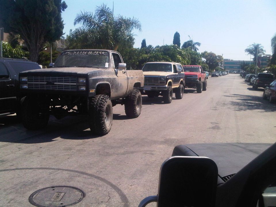 Line of lifted trucks and SUVs, including a Chevrolet pickup and Ford Bronco