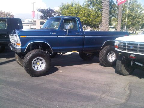 1986 Ford Bronco - A lifted blue 1979 Ford F-150 pickup truck is parked next to another vehicle.