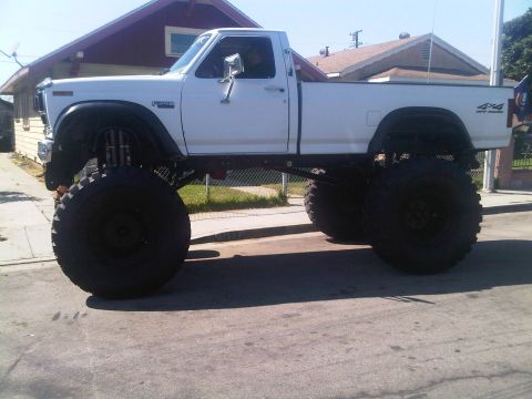 1986 Ford Bronco - This lifted pickup truck features oversized tires and a significant suspension lift, giving it a commanding presence.