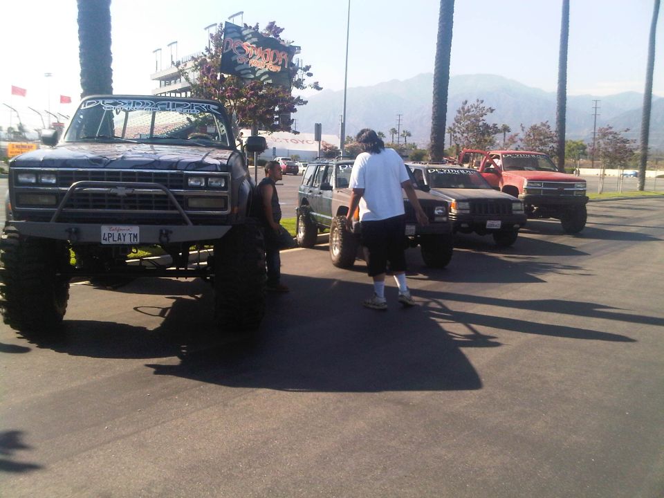 Dark blue pickup truck with large tires and custom bumper, front view. License plate reads '4PLAY TM'