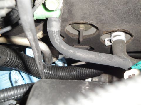 2003 Ford Taurus - Close-up view of automotive AC lines and a wiring harness, with a mechanic's gloved hands present.