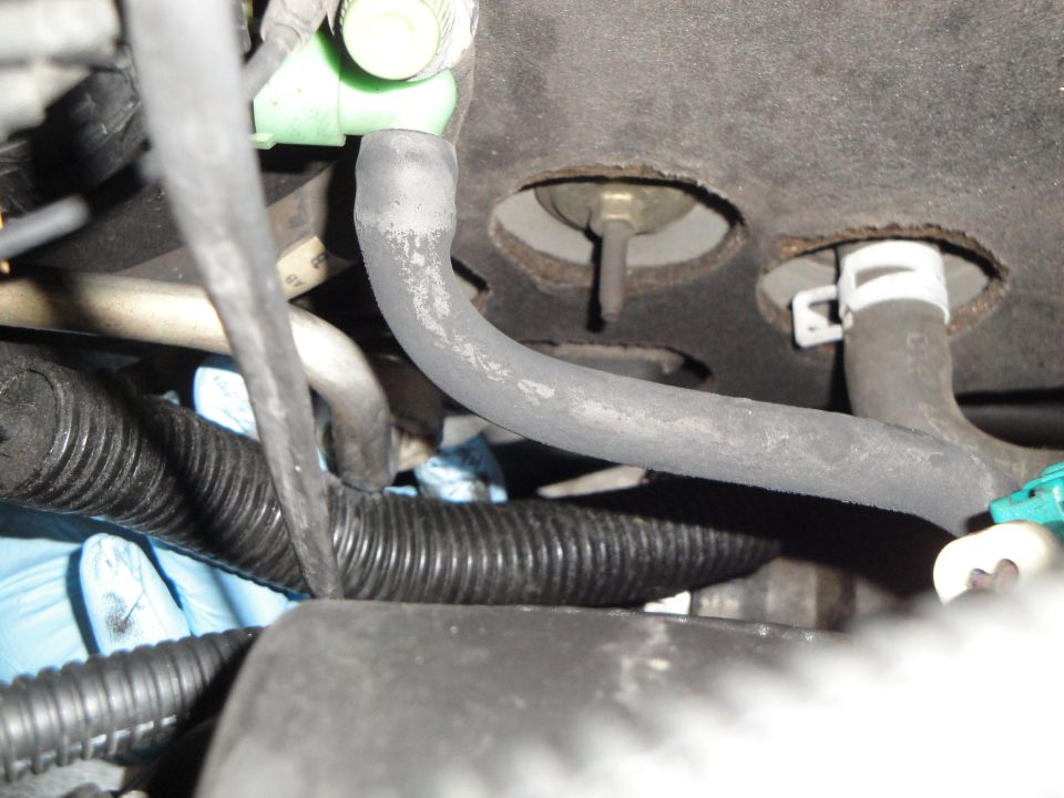 Close-up of AC lines and a black corrugated wiring harness, with blue gloved hands visible