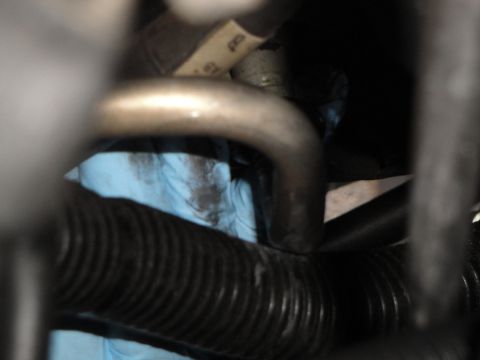 2003 Ford Taurus - A close-up view of automotive AC lines and hoses, with a mechanic's blue gloves visible.