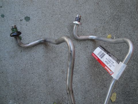 2003 Ford Taurus - Two metal AC lines are shown on a concrete surface. One has a Ford Motorcraft label.