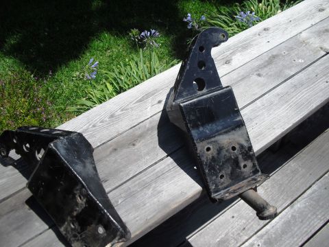 1986 Ford Bronco - Pair of black metal suspension components shown outdoors on a wooden surface.