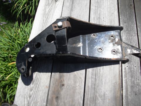 1986 Ford Bronco - A black metal suspension component, likely a coil bucket, is shown resting on weathered wooden planks.