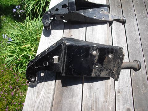1986 Ford Bronco - Two black metal suspension parts are laid out on a wooden deck with greenery in the background.