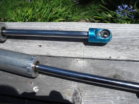 1986 Ford Bronco - Two shock absorbers are shown, one with a distinctive blue end fitting, laid out on weathered wooden planks.
