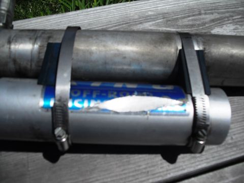1986 Ford Bronco - Close-up of an exhaust pipe a blue label that reads 'OFF-ROAD RACING', secured with metal clamps.
