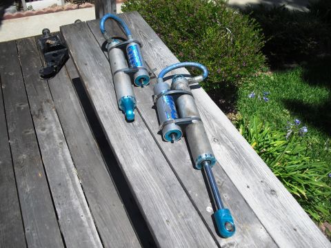 1986 Ford Bronco - Pair of King Off-Road Racing shocks shown on a weathered wooden table outdoors.