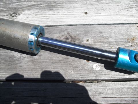 1986 Ford Bronco - A shock absorber with blue accents rests on weathered wooden planks. The registry claims it is from a 1986 Ford Bronco.