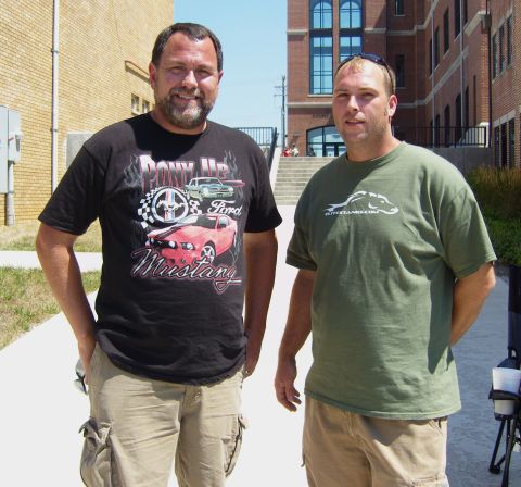 2007 Ford Mustang - Two men pose for a photo outside a brick building on a sunny day. One man wears a t-shirt a Ford Mustang.