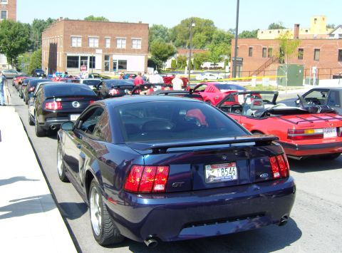 2007 Ford Mustang - A line of Ford Mustangs parked on a street, with a dark blue GT in the foreground.