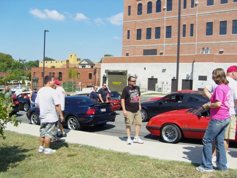 2007 Ford Mustang - Several Ford Mustangs are gathered outdoors with people milling about.