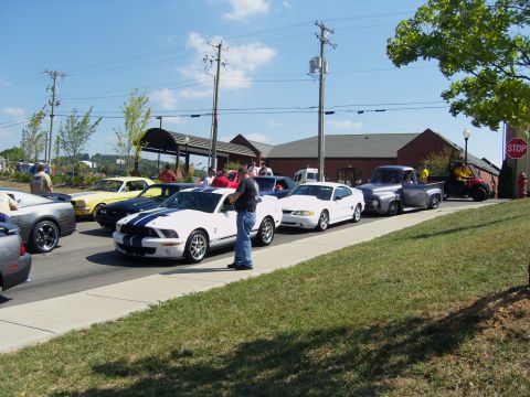 2007 Ford Mustang - Several cars, including a white 2007 Ford Mustang GT, are parked on a street.