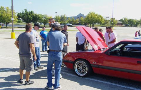2007 Ford Mustang - Group of people looking at a red coupe with its hood open in a parking lot.