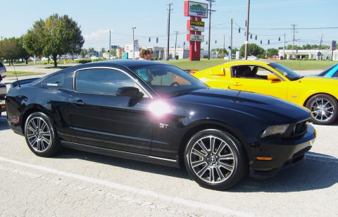 2007 Ford Mustang - A black Ford Mustang GT is parked next to a yellow car, with a sign in the background.
