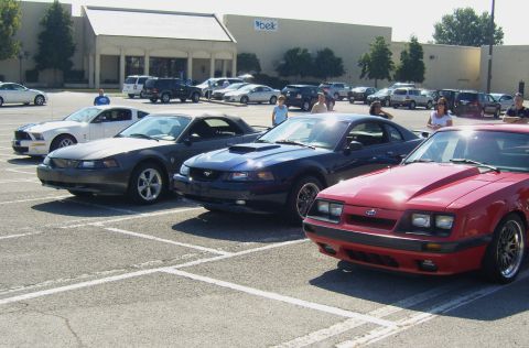 2007 Ford Mustang - A red fox body Mustang is parked in a lot with other vehicles.