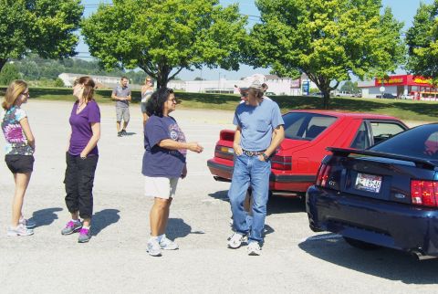 2007 Ford Mustang - Two Ford Mustangs are parked in a lot, one red and one dark blue, with people standing around them.