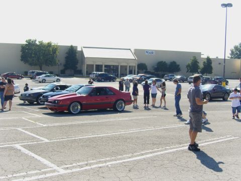 2007 Ford Mustang - A red fox body Mustang is the focus of this parking lot gathering, with several other vehicles visible.