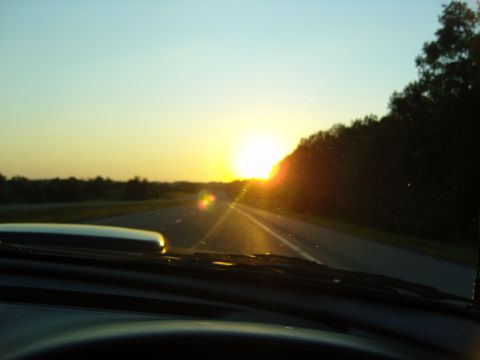 2007 Ford Mustang - Driving into the sunset on a highway, with the sun casting a warm glow over the road ahead.