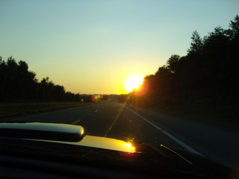 2007 Ford Mustang - Driving on the highway as the sun sets, casting a warm glow over the landscape.