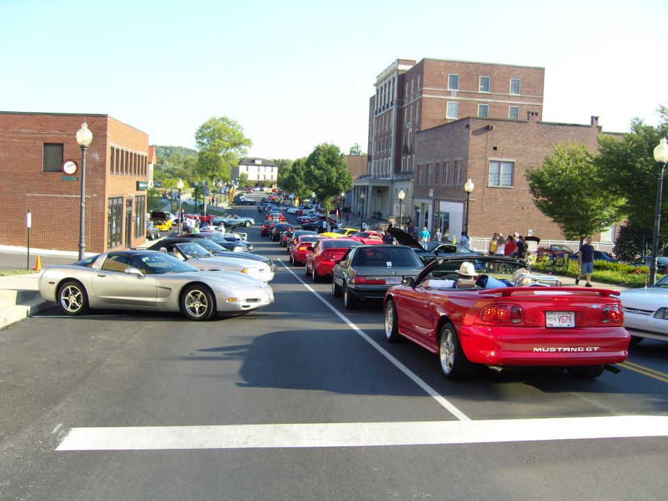 Red convertible Mustang GT with a license plate V679 parked on a street with other cars