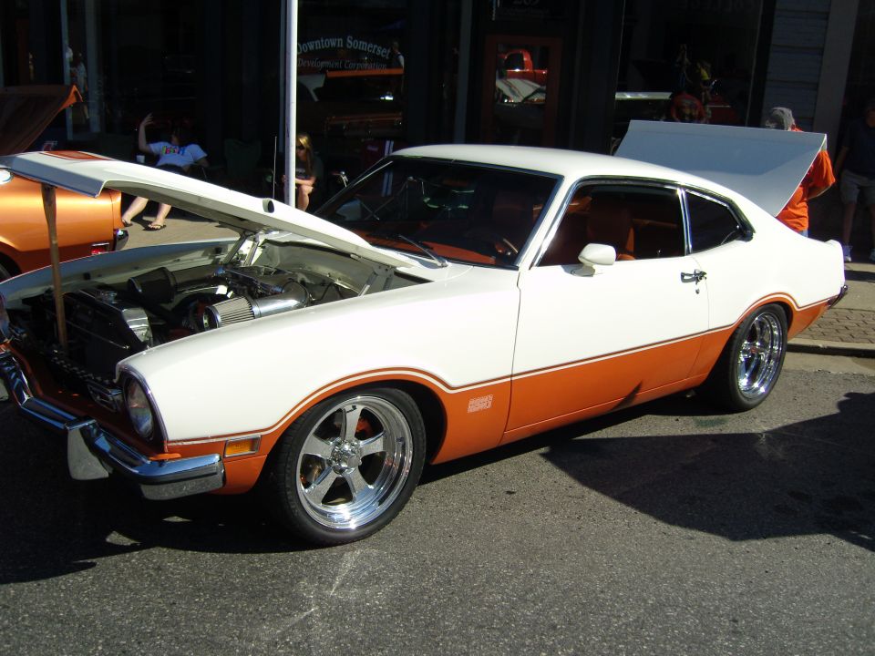White and orange 1970 Ford Maverick with hood and trunk open, showing engine