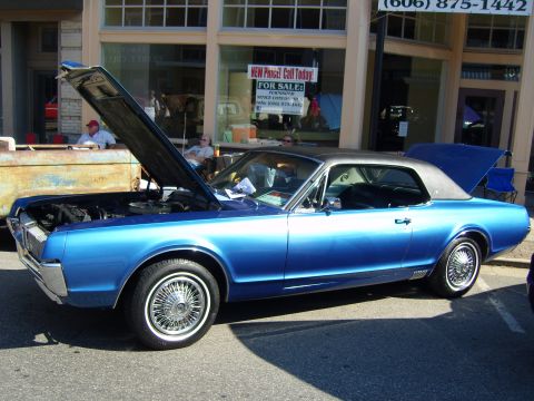2007 Ford Mustang - Classic blue coupe with hood and trunk open, parked on a street with buildings in the background.