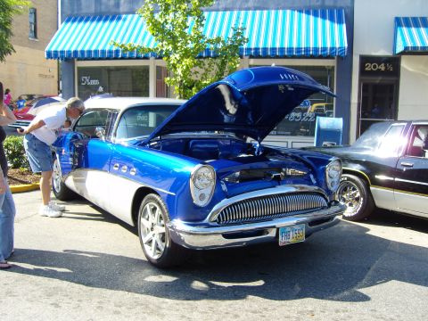 2007 Ford Mustang - A classic Buick is displayed with its hood open at an outdoor event, parked next to another vehicle.