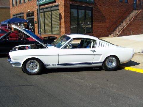 2007 Ford Mustang - Side view of a white 1965 Ford Mustang GT Fastback with hood open, parked on street.