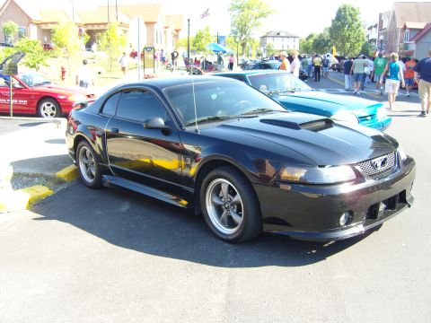 2007 Ford Mustang - A black Ford Mustang is parked at an outdoor car show with other vehicles and people in the background.