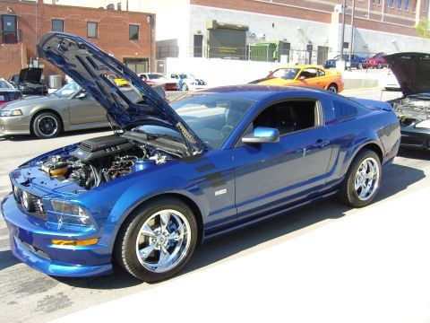 2007 Ford Mustang - A blue 2007 Ford Mustang is displayed with its hood open, revealing the engine compartment.
