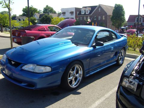 2007 Ford Mustang - A blue 1994 Ford Mustang GT is parked next to other vehicles, with a custom hood scoop and chrome wheels.