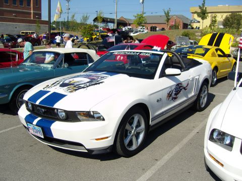 2007 Ford Mustang - A white 2007 Ford Mustang convertible, adorned with blue racing stripes and patriotic eagle decals, is parked at a car show.