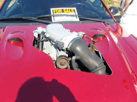2007 Ford Mustang - A red car with its hood open reveals the engine and a "FOR SALE" sign placed on the windshield.