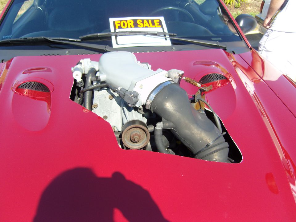 Red car engine with "FOR SALE" sign on hood
