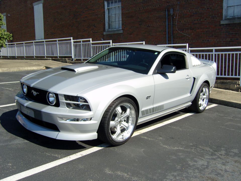 Silver 2007 Ford Mustang GT parked in a lot, showing front quarter view with racing stripes
