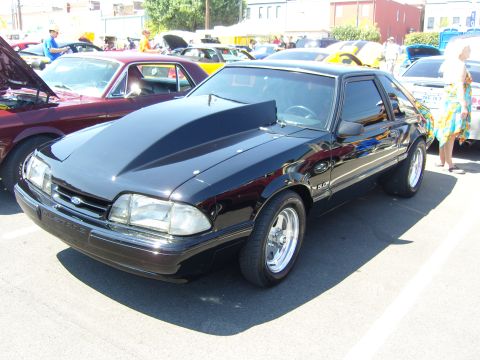 2007 Ford Mustang - Black Ford Mustang with a prominent hood scoop and "5.0" badging is parked at an outdoor car show.