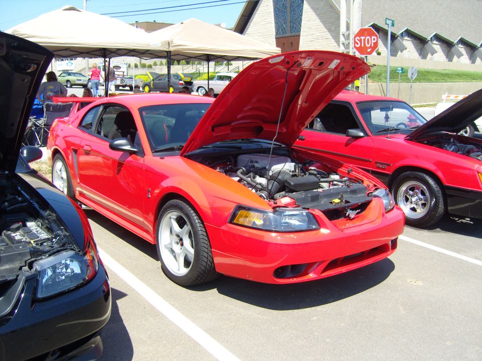 Red 2007 Ford Mustang with hood open, parked next to other cars