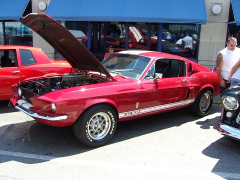2007 Ford Mustang - A classic red 1967-1968 Ford Mustang GT 500 is displayed with its hood open, parked next to another vehicle.