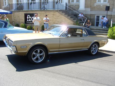 2007 Ford Mustang - A classic gold Mercury Cougar is parked on the street in front of a building with stairs.