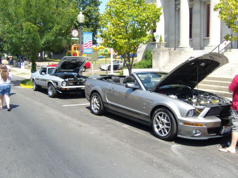 2007 Ford Mustang - A silver 2007 Ford Mustang GT500 convertible is displayed with its hood open, alongside another classic Mustang.
