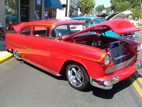 2007 Ford Mustang - A bright red 1955 Chevrolet Bel Air is displayed with its hood open at a car show.