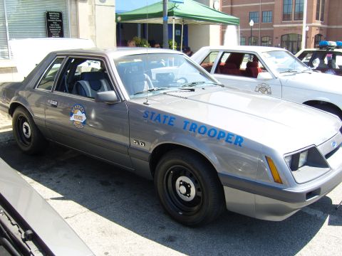 2007 Ford Mustang - A vintage Ford Mustang, marked as a State Trooper vehicle, is parked alongside other police cars.