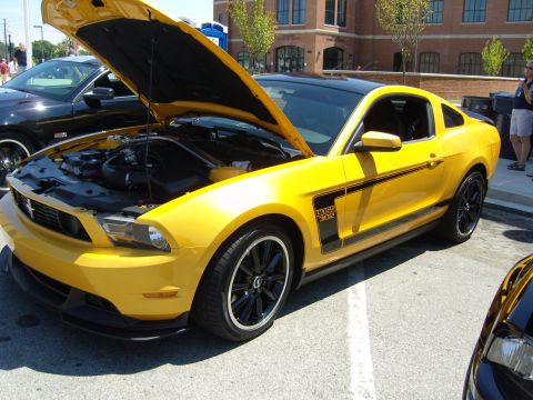 2007 Ford Mustang - A yellow Ford Mustang Boss 302 is displayed with its hood open, parked next to another vehicle.