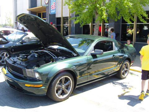 2007 Ford Mustang - A green coupe is displayed with its hood open, parked alongside another vehicle at an outdoor event.