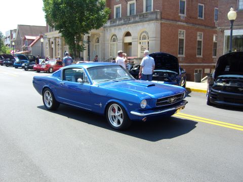 2007 Ford Mustang - A line of cars, including a blue classic Ford Mustang, are parked on a street in front of buildings.