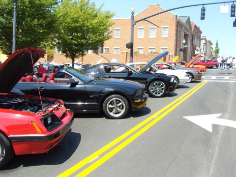 2007 Ford Mustang - Several Ford Mustangs are parked on a street with their hoods open, suggesting a car show or gathering.